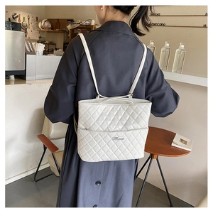 Detailed close-up of white quilted faux leather backpack showing fine diamond stitch texture