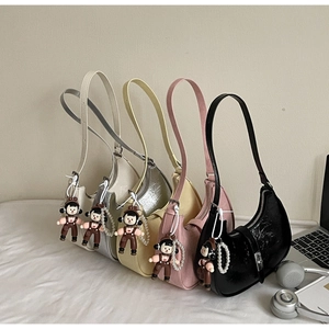 Detail of trendy dumpling bags with glossy texture, pearl chains and cute doll charms