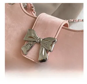 Détail du sac en cuir rose clair avec une grande boucle en forme de nœud argenté