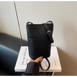 Detail of black bucket bag showing pebbled leather texture and adjustable strap
