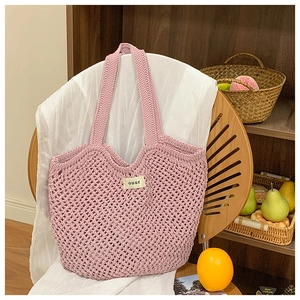 Gros plan du sac fourre-tout en maille rose tissée avec une étiquette en tissu ouur épurée