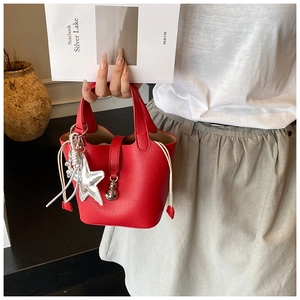 Detalle del bolso de cubo rojo con grabado de lichi, colgante estrella y bolsa interna