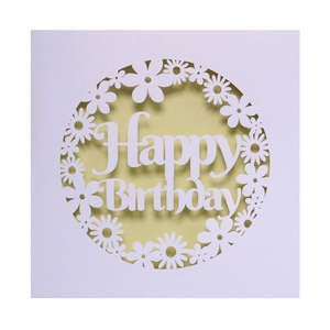 Macro shot of laser-cut floral daisy patterns on a white Happy Birthday greeting card