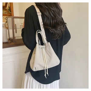 Detail of beige nylon drawstring bucket bag showing adjustable woven strap and soft texture