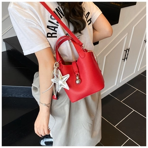 Detalle del bolso de cubo rojo con textura litchi y colgantes de estrella plateada