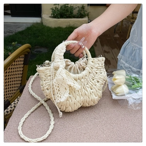 Detail of woven straw handbag with lace bow and drawstring inner bag for beach vacation