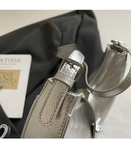 Detail of adjustable silver shoulder strap with polished metal buckle on pleated bag