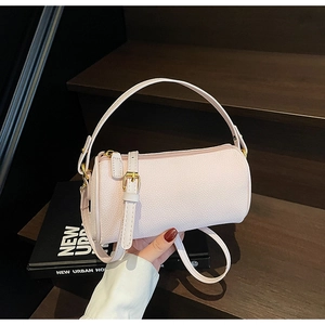 Detail of light pink cylindrical crossbody bag with pebble grain texture and gold hardware