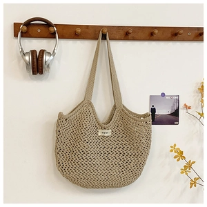 Détail d'un sac cabas en crochet beige avec étiquette ouur suspendu à un crochet
