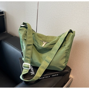 Detailed texture of green pleated nylon crossbody bag with adjustable white strap buckle