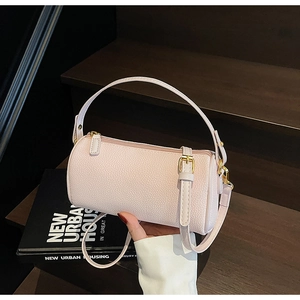 Close-up of pink litchi grain leather pillow bag with gold zipper on a wooden stair