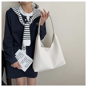 Close-up of the V-shaped woven texture and smooth strap of the off-white tote bag