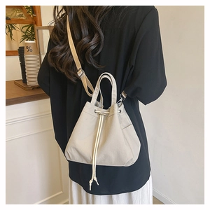 Close-up of beige nylon drawstring bucket bag with adjustable strap in a cafe setting
