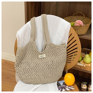 Détail de la texture en maille et étiquette ouur sur le sac à bandoulière tressé beige