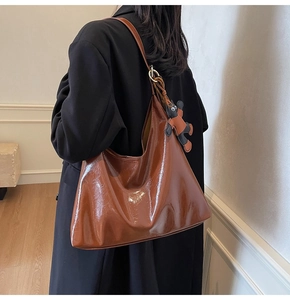 Detail of caramel glossy tote bag with crinkled texture and cute bear charm pendant