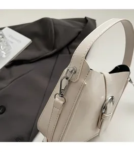 Detail of cream white leather bucket bag with silver hardware and knit strap textures