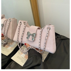Détail du sac baguette rose clair avec ornement nœud argenté et bandoulière chaîne