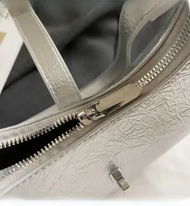 Detailed close-up of smooth silver zipper on crinkled metallic texture handbag