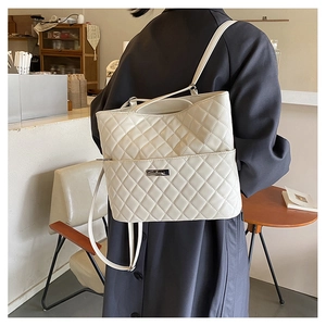 Detail of white quilted PU leather backpack with metallic logo plate on model