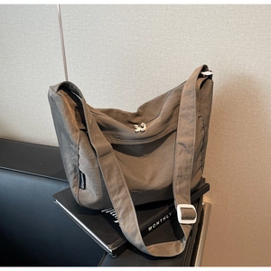Close-up of large nylon crossbody bag with adjustable wide strap on black magazine