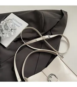 Detail of creamy white bucket bag featuring pebble grain leather and silver metal ring