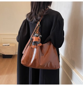 Close-up of brown patent leather tote bag with a cute cat charm detail on the side