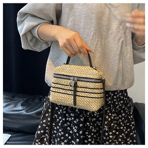Détail du sac en paille tissé avec rayures noires, fermeture éclair à anneau et sangle