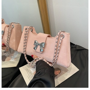Gros plan du sac baguette en daim rose avec nœud en métal argenté et bandoulière
