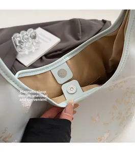 Detail view of the magnetic buckle closure and golden embroidery on the tote bag