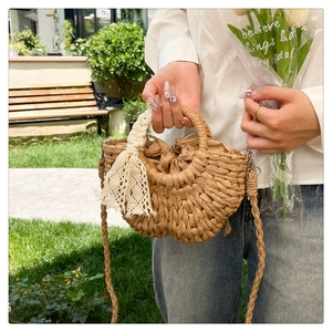 Detail of hand-woven semi-circle straw bag featuring lace trim and drawstring closure