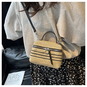 Détail du sac bandoulière en paille tressée avec poignée en cuir noir et fermeture éclair