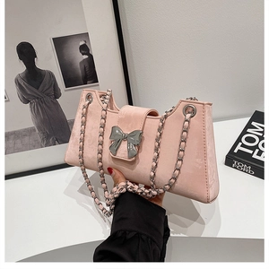 Détail du sac baguette en velours rose avec fermoir nœud argenté et bandoulière chaîne