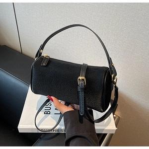 Close-up of black cylinder bag with pebbled leather texture and gold hardware detail