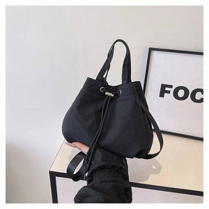 Detailed shot of the black nylon bucket bag with a secure drawstring and silver metal clasp