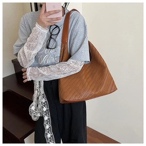 Brown woven hobo tote bag worn by a model showcasing its large capacity and V-shaped texture