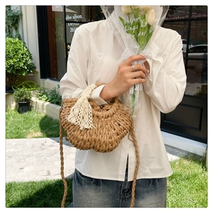 Detail of a handmade straw bag with intricate weaving and a white lace floral ribbon