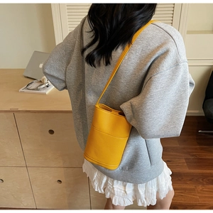 Detail of yellow lychee grain leather bucket bag shown on model in a cozy home setting