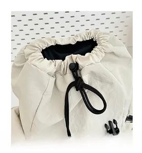 Close-up of cream nylon travel backpack featuring adjustable drawstring closure and buckle