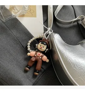 Detail of a cartoon girl doll charm with white pearl chain hanging on a silver bag