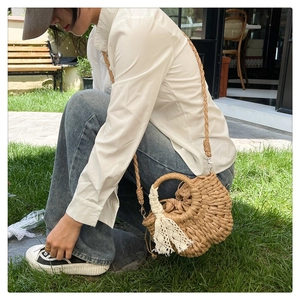 Sac de plage tressé avec ruban en dentelle et poignée ronde sur herbe en extérieur