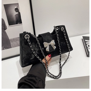 Détail du nœud métallique argenté sur sac à bandoulière noir avec chaîne tressée