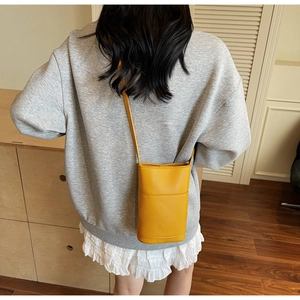Close-up of minimalist yellow textured crossbody phone bag worn by a model
