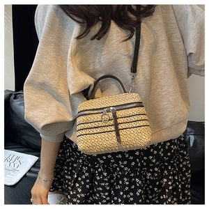 Détail du sac bandoulière beige tissé main avec poignée en cuir noir et fermeture éclair