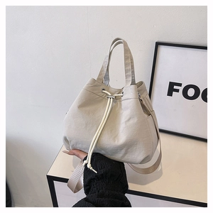Detail of cream drawstring bucket bag showing durable nylon texture and side pocket