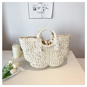 Detail of hand-woven straw tote bag featuring white floral lace handles and drawstring liner