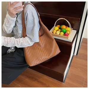 Detail of caramel brown woven leather texture on a hobo shoulder bag shown on stairs