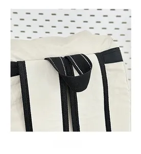 Detail of reinforced travel backpack handle with black webbing and reflective stitching