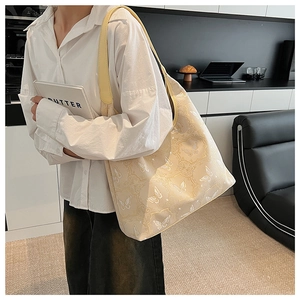 Détail d'un sac cabas crème avec broderie papillon et bandoulière en cuir jaune