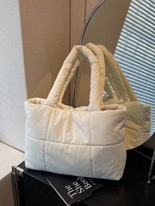 Sac fourre-tout matelassé crème avec poignées rembourrées sur une surface noire élégante