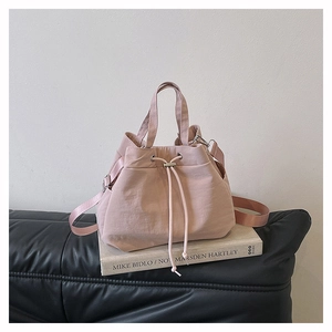 Detail of light pink nylon bucket bag with drawstring closure on book display
